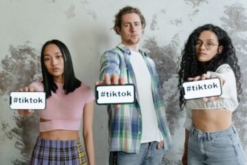Diverse group of young adults holding smartphones displaying #tiktok hashtag.