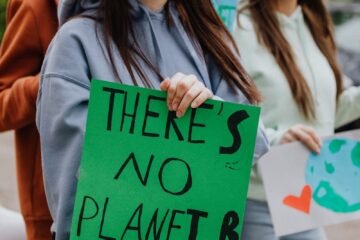 Youth at climate protest rally, holding signs for environmental awareness and change.