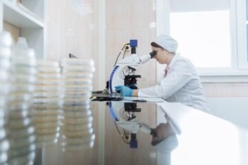 Female scientist using a microscope in a laboratory environment, focusing on research.