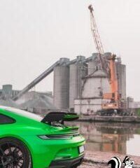 a bright green sports car parked in front of a factory