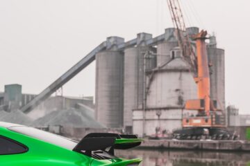 a bright green sports car parked in front of a factory
