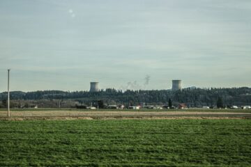 a green field with a power plant in the background