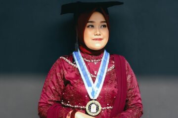 A woman poses in her graduation attire.