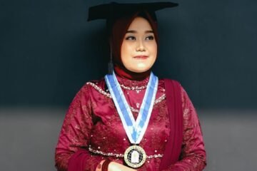 A woman poses in her graduation attire.