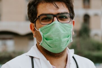man in white scrub suit wearing green mask