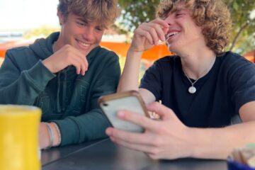 two people sitting at a table with a tablet