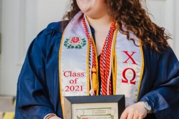 woman in blue and white academic dress holding certificate