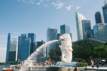 A statue of a dog spewing water in front of a city skyline