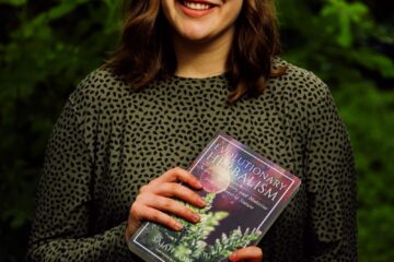 A woman sitting on a bench holding a book