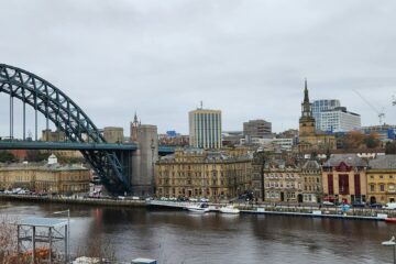 a bridge over a river with a city in the background