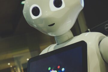 white robot toy holding black tablet