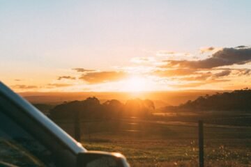golden hour photography of vehicle park near fence