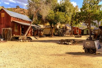 A dusty, old western town with wooden buildings.