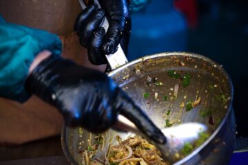 a person in gloves and gloves stirring food in a bowl