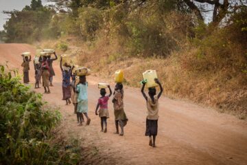 group of people walking at the road carrying containers