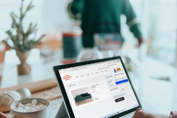 Person on their Surfacelaptop online shopping drinking hot chocolate with person in background out of focus